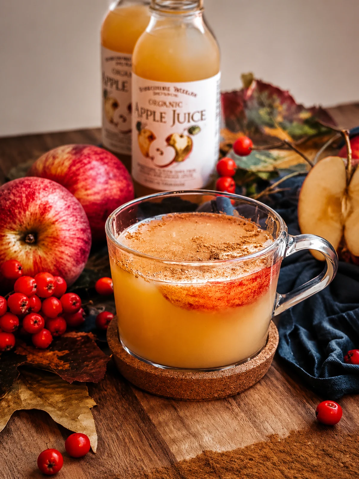 A warm spiced apple drink surrounded by apples and autumn berries