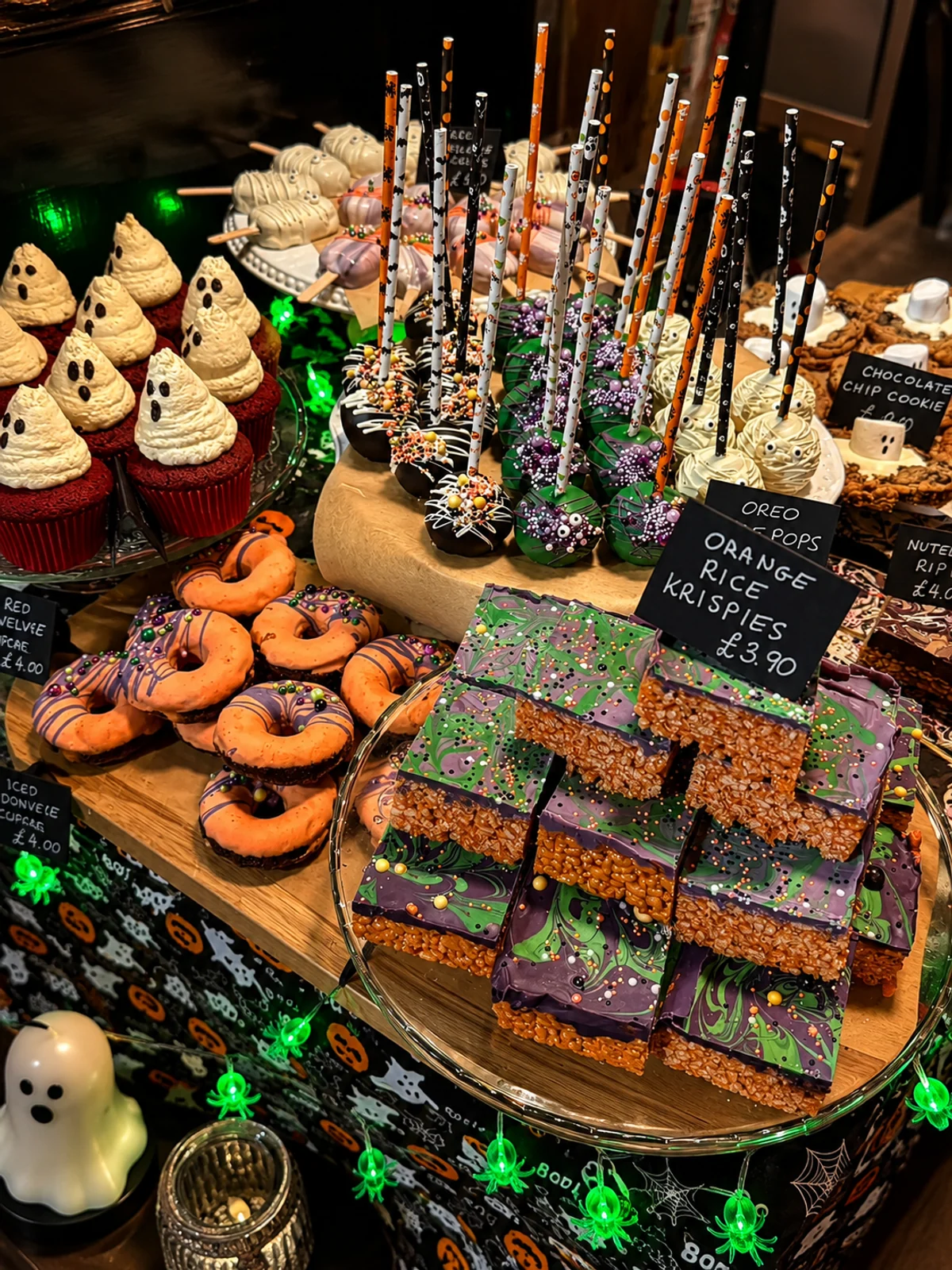 A colourful Halloween display of cupcakes, doughnuts, cake pops and crisped rice treats